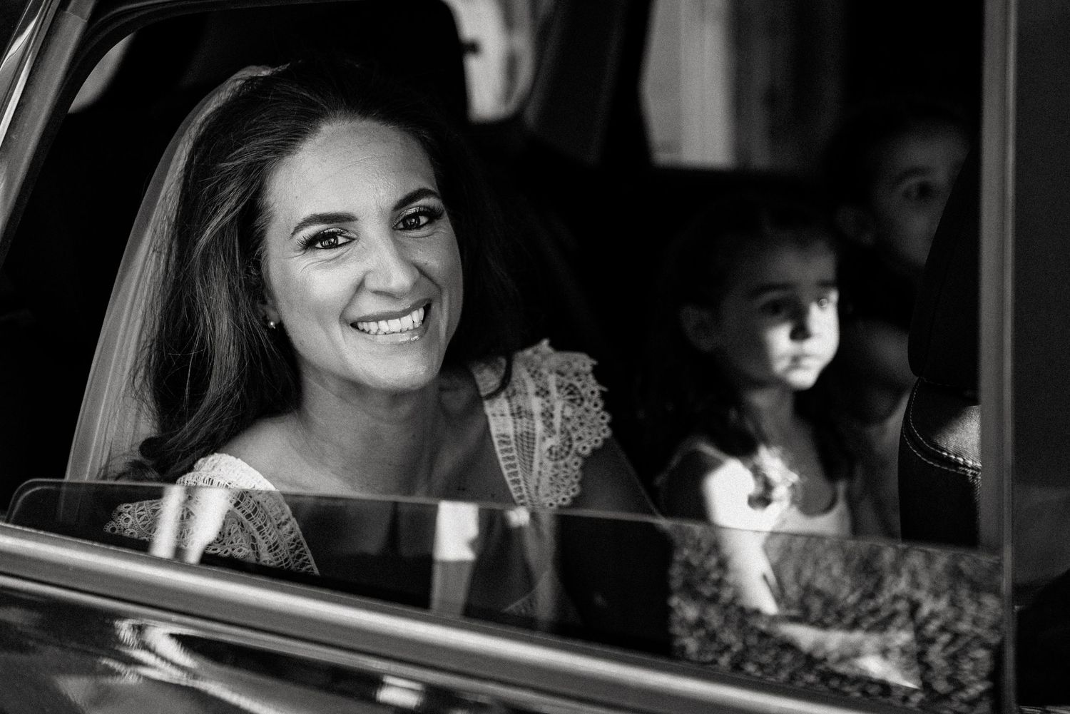 Wedding party members share joyful moments in a car during the celebration.