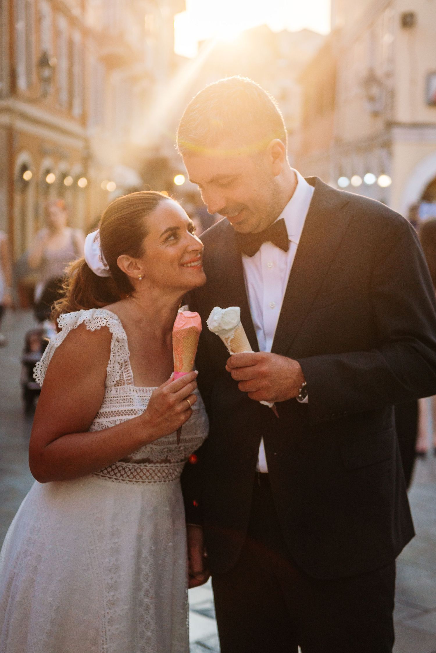 Newlyweds sharing ice cream and laughter during their evening wedding celebration.