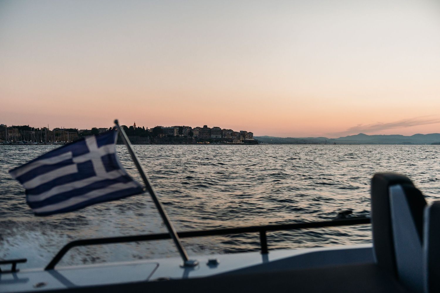 Panoramic sunset view of Mediterranean coastline with mountains in distance.