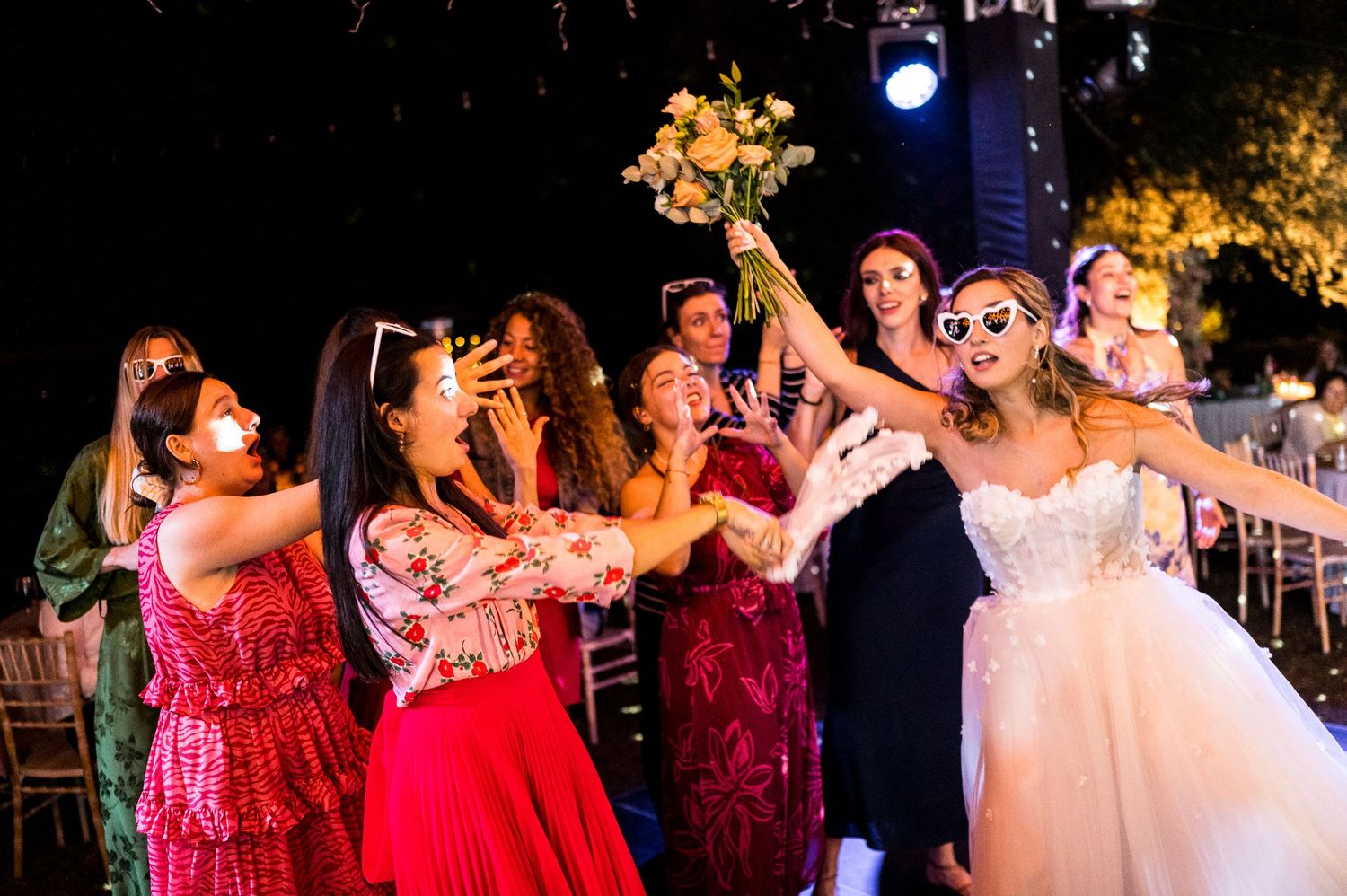 Wedding celebration with guests in red dresses dancing together on the dance floor.