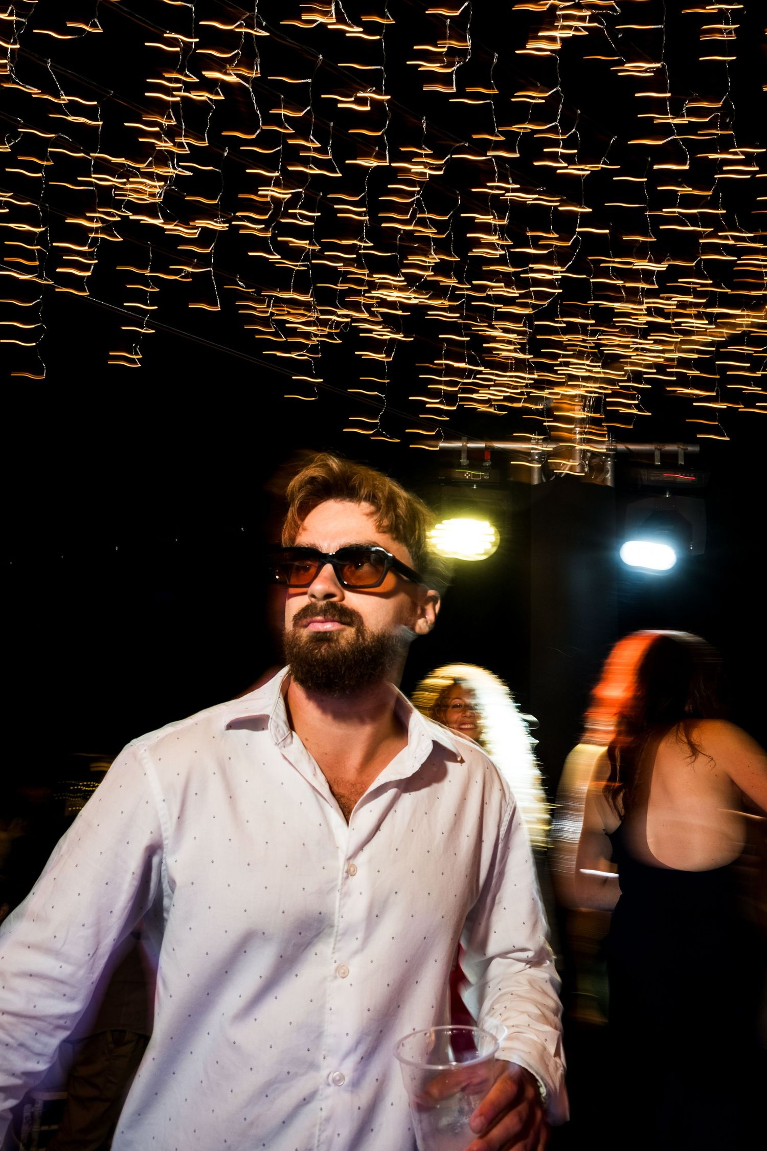 String lights create dramatic ceiling pattern above dance floor at wedding reception.