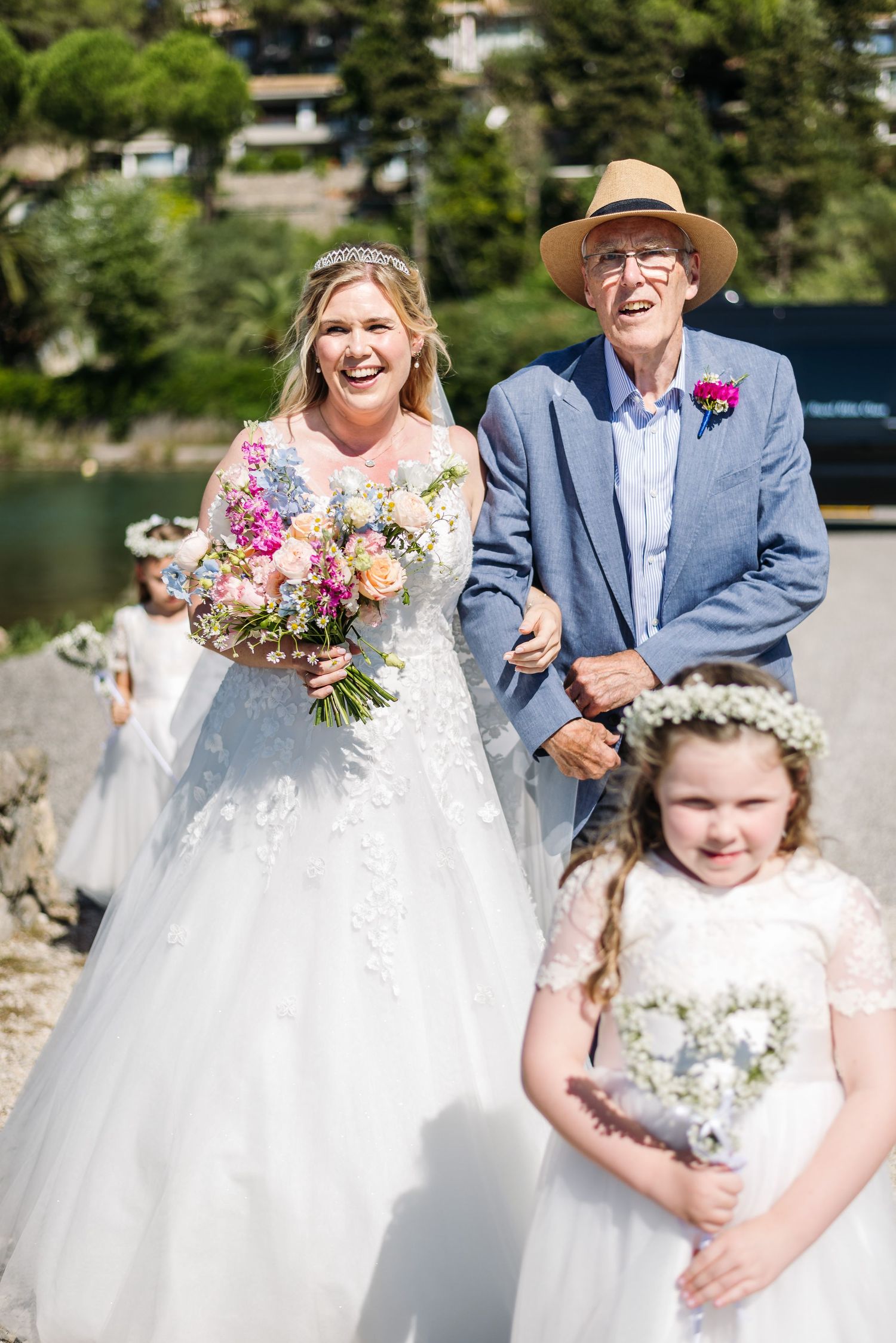 Wedding party members in formal attire gather outdoors on a sunny day.