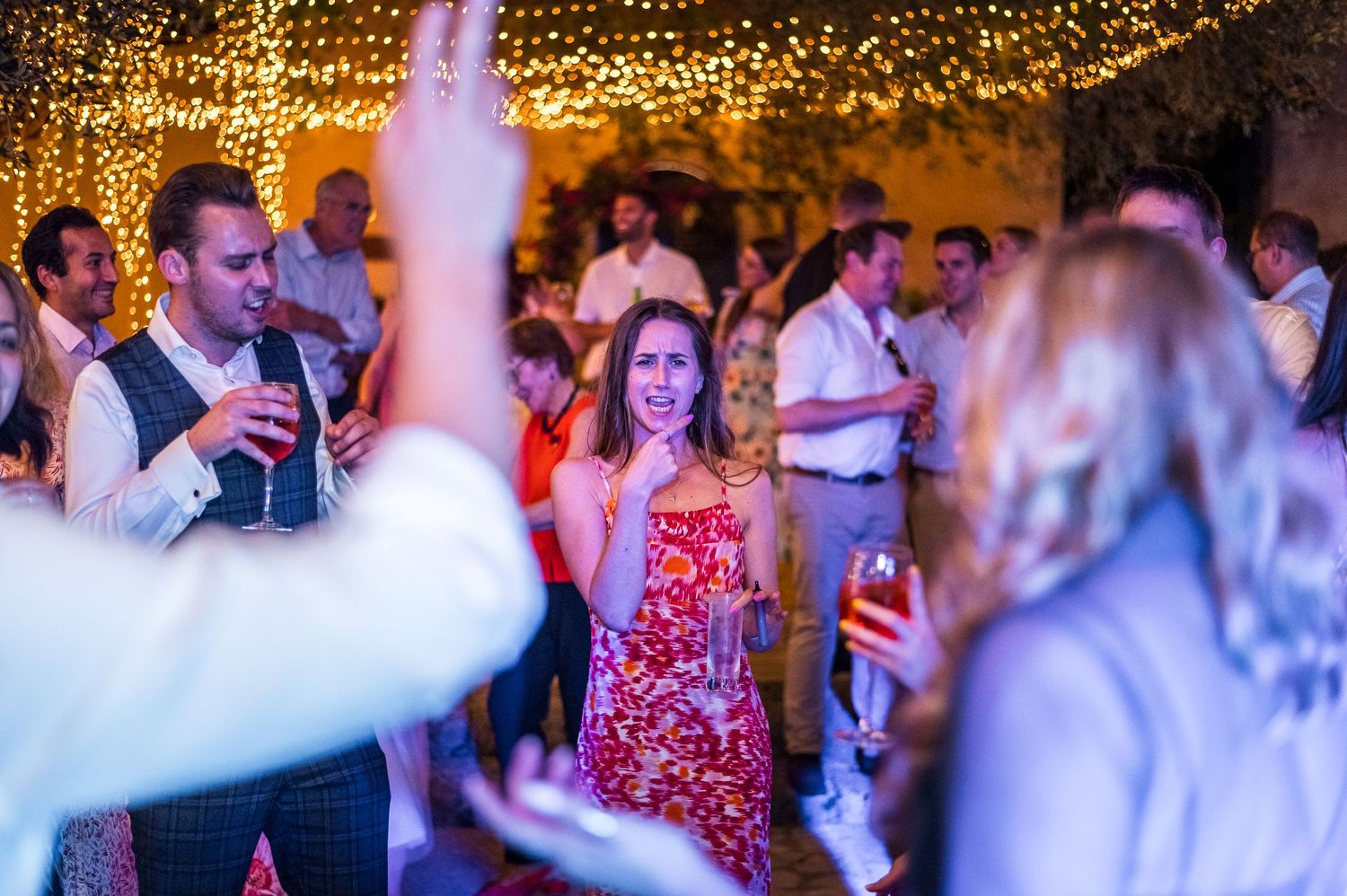 Celebration under warm string lights with people dancing and enjoying the festive atmosphere.
