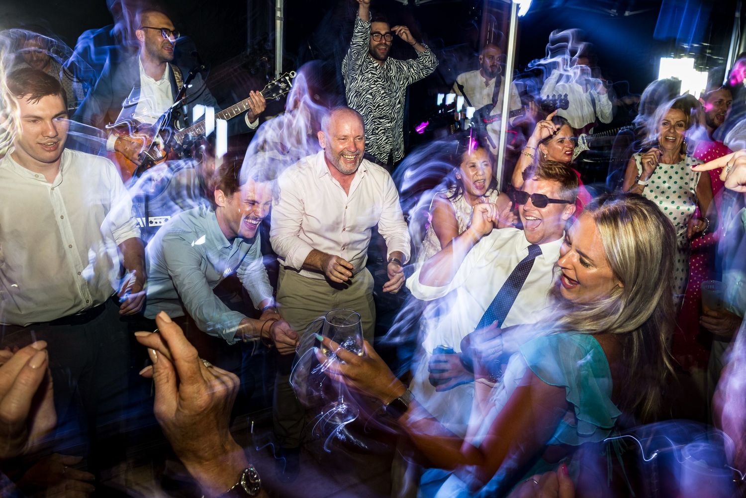 Lively dance floor scene with party guests moving under dramatic blue lighting.