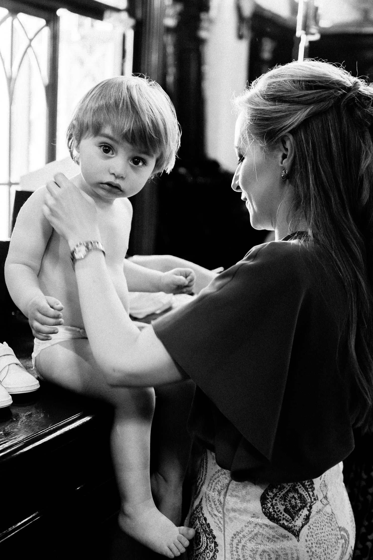 Series of tender black and white photos showing a baby being held during a baptism ritual.