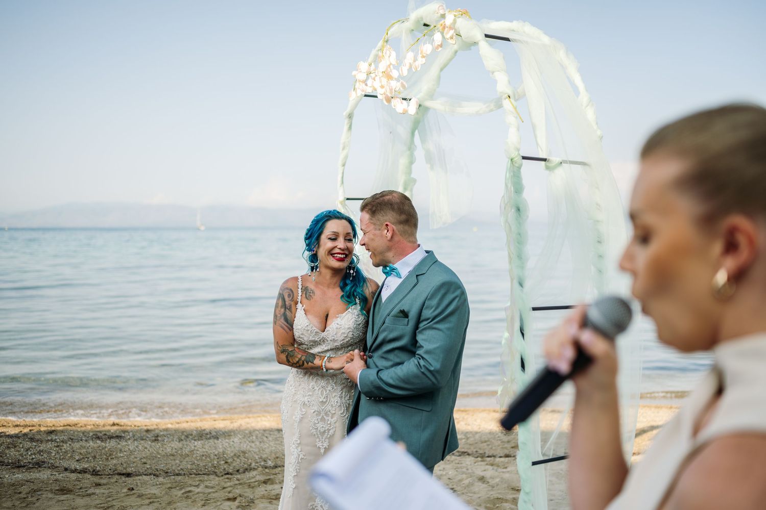 Beachside wedding ceremony with white arch and ocean backdrop.