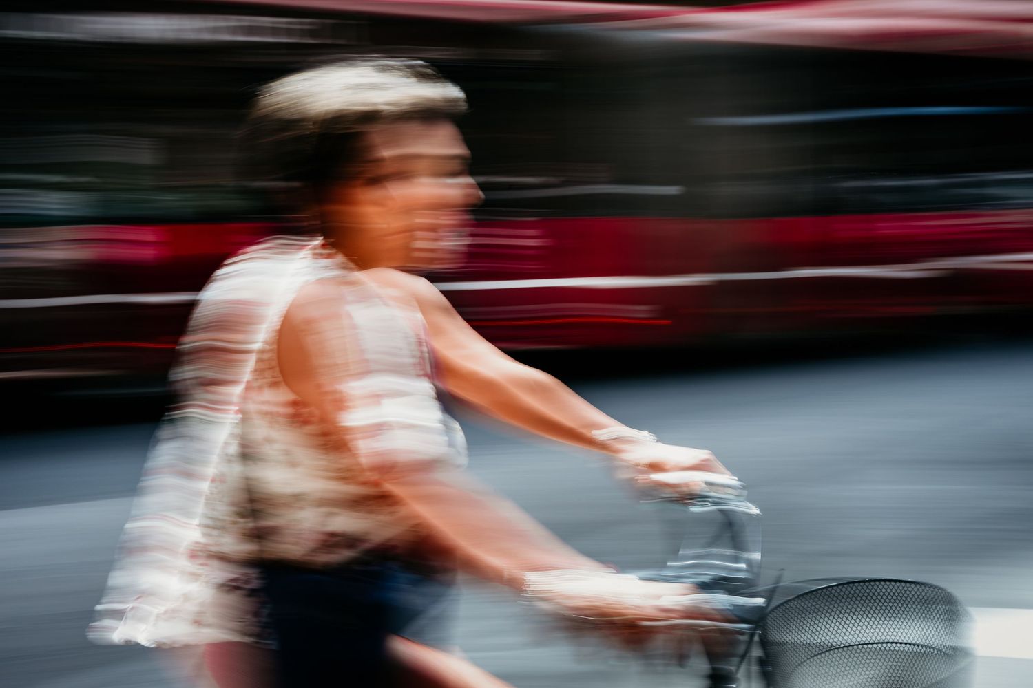 Motion-blurred photograph of cyclist riding past urban scenery.