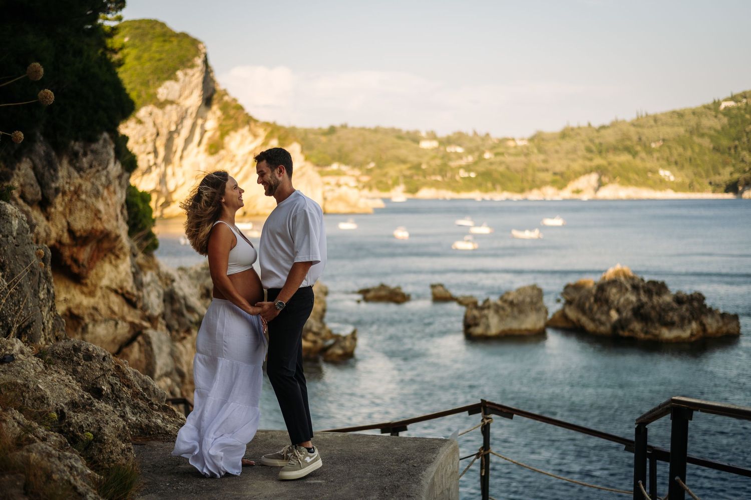 Romantic couple embraces on a scenic coastal overlook during golden hour with ocean views.