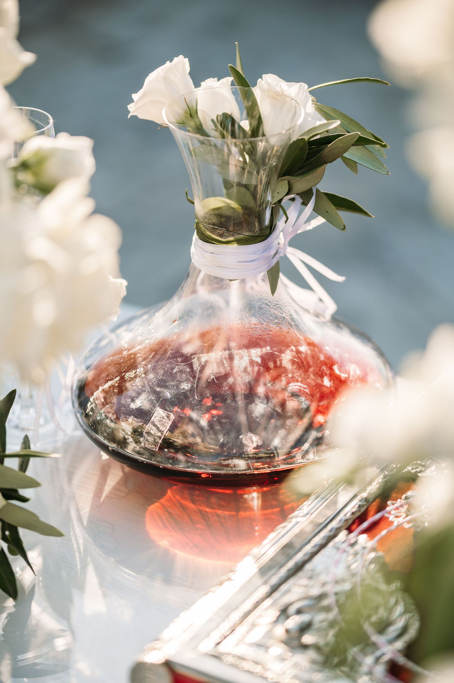 Close-up of rose-colored drinks in glass vessels decorated with white flowers.