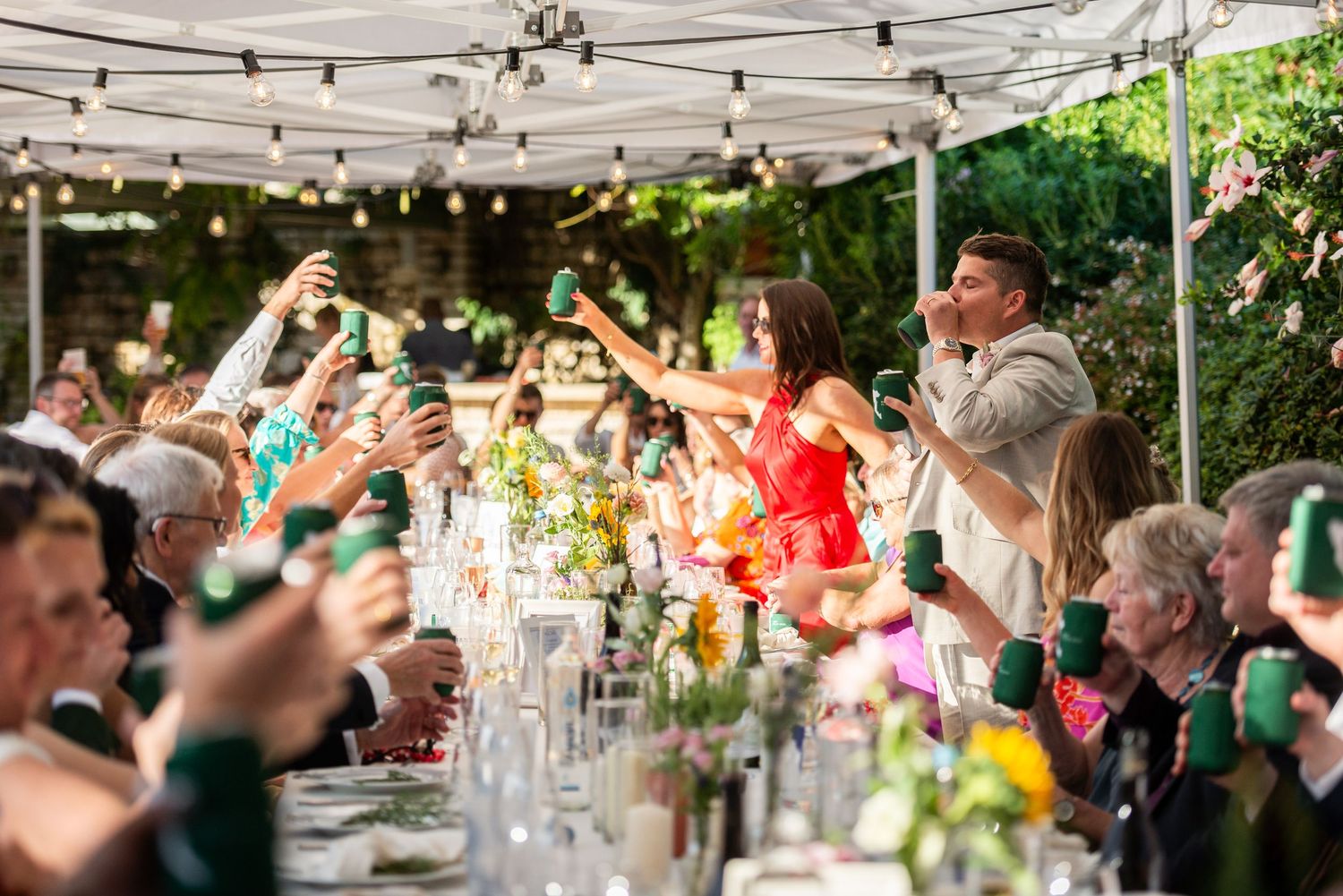 Wedding guests enjoying a celebration under string lights and white canopy tents.
