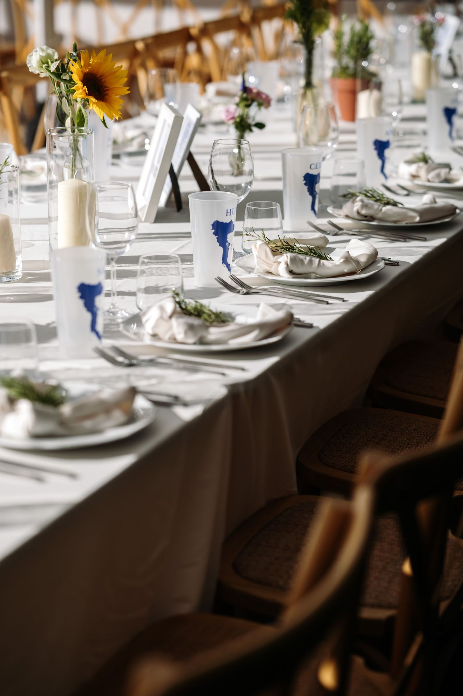 Elegant wedding table settings with sunflowers and blue accents on crisp white linens.