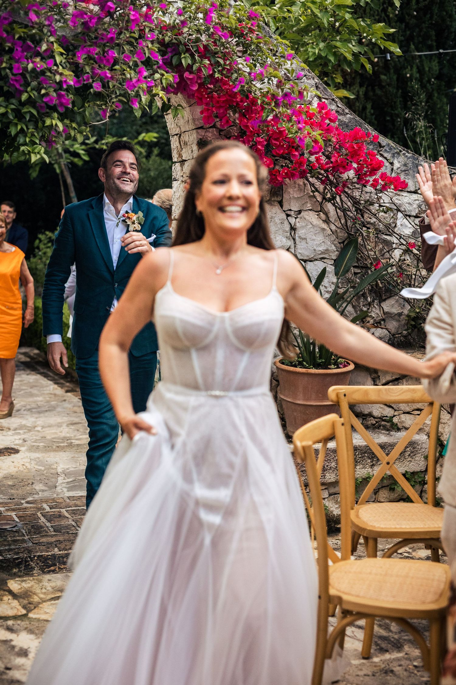 A celebration in a garden courtyard with vibrant bougainvillea flowers and wooden chairs.
