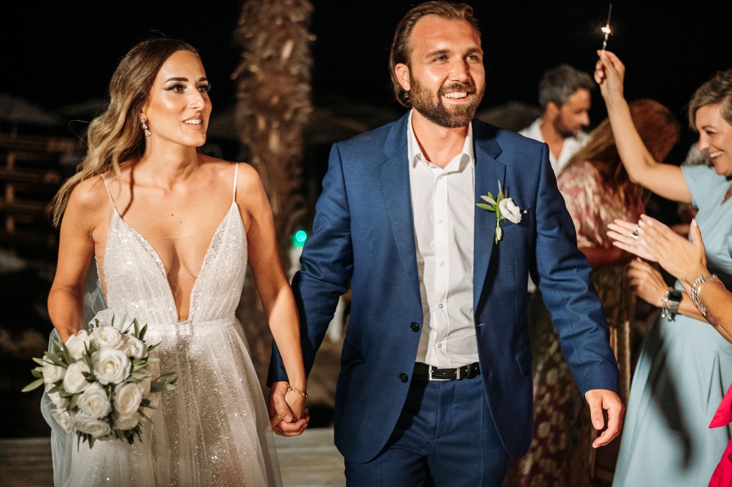 Wedding party members walking together in formal attire at an outdoor venue.