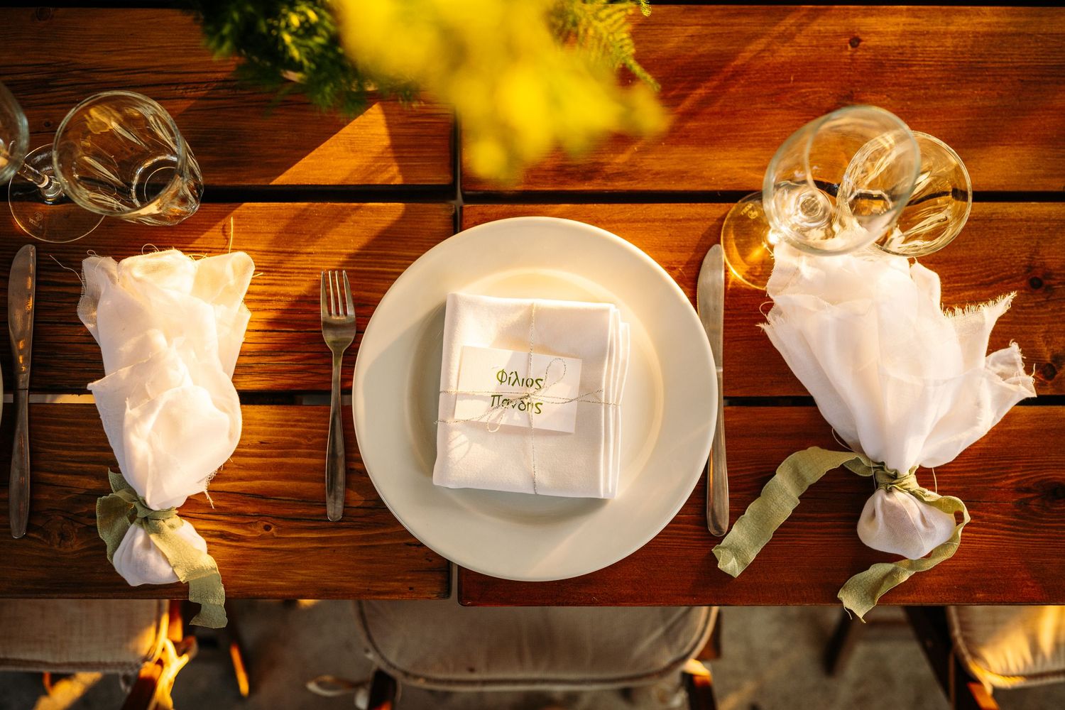 Elegant place settings with white napkins and plates arranged on a wooden table.