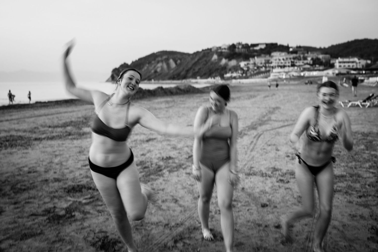 Playful beach photoshoot with people jumping and having fun by the ocean.