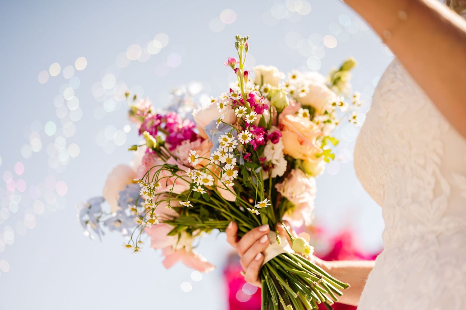 Close-up of pink and white floral wedding decorations against blue sky.