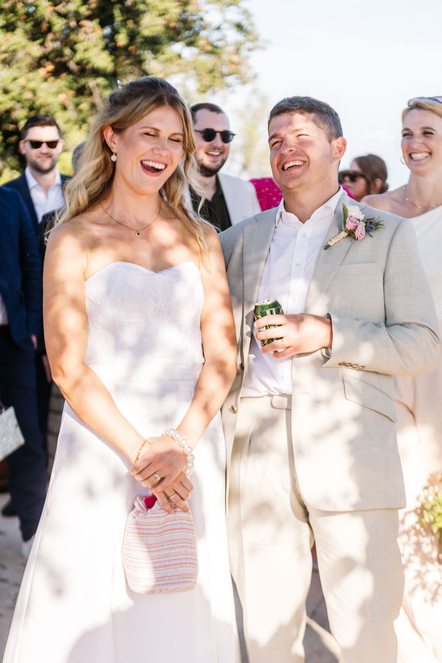 Wedding party dressed in elegant cream and white attire standing together outdoors.