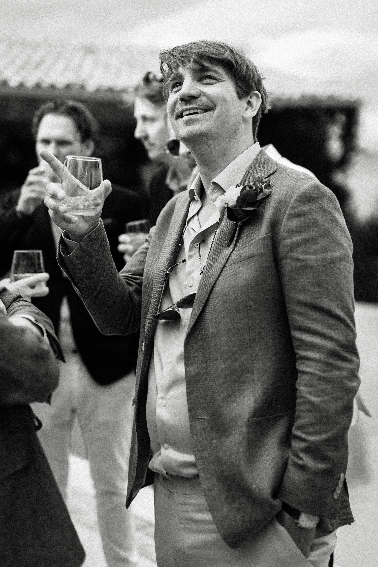 Black and white candid photo of guests laughing and raising glasses at a celebration.