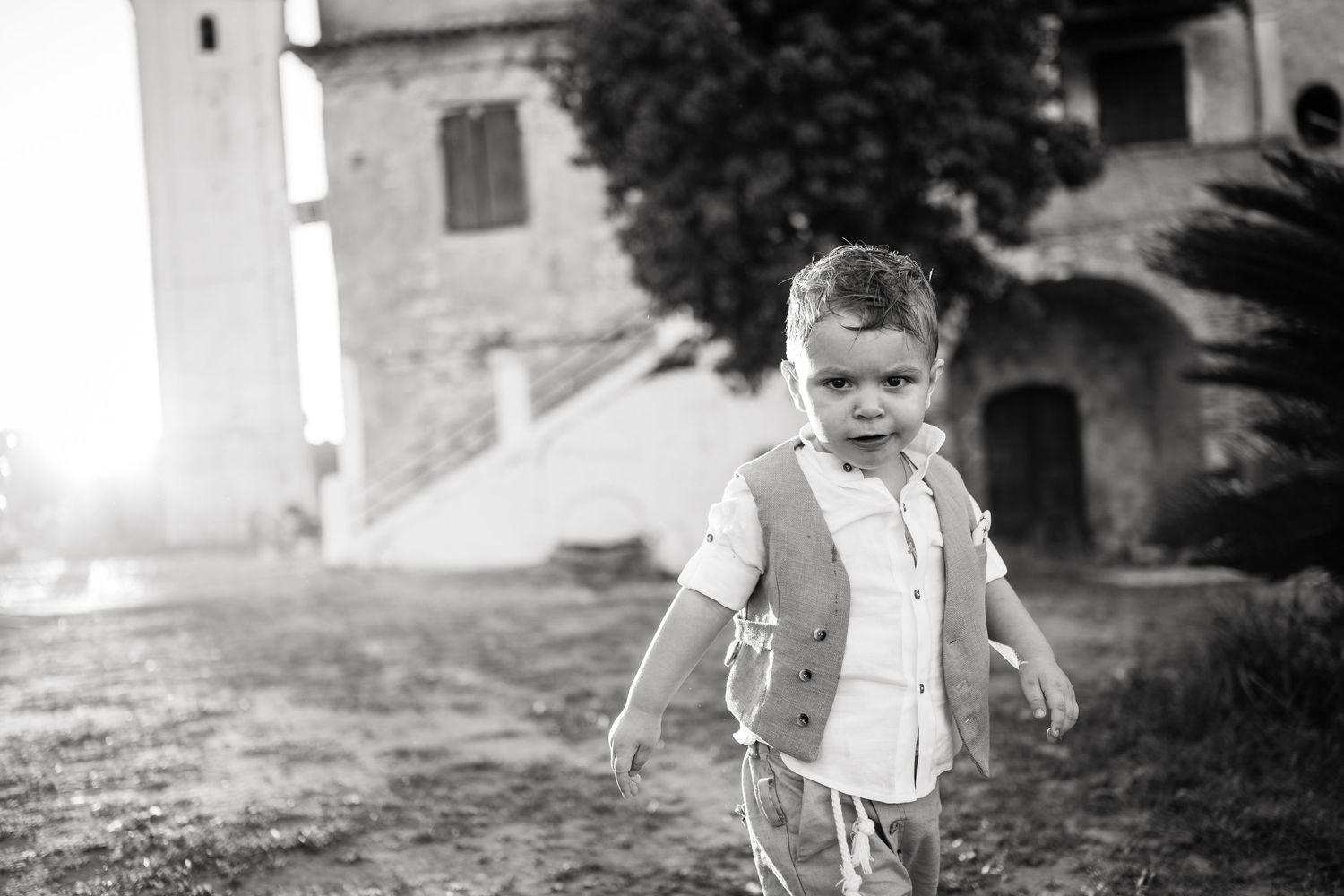 Black and white photo of a small child walking outdoors near a historic building.