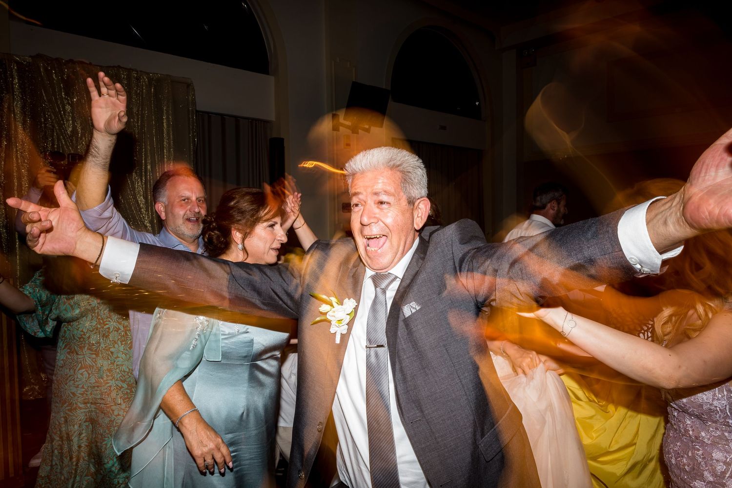 Wedding guests dancing enthusiastically at a lively reception party.