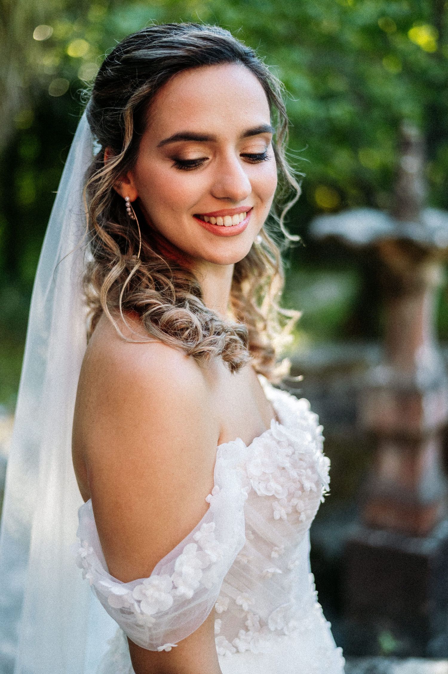 Close-up bridal portraits showing an off-shoulder white lace wedding dress and delicate veil against a natural background.
