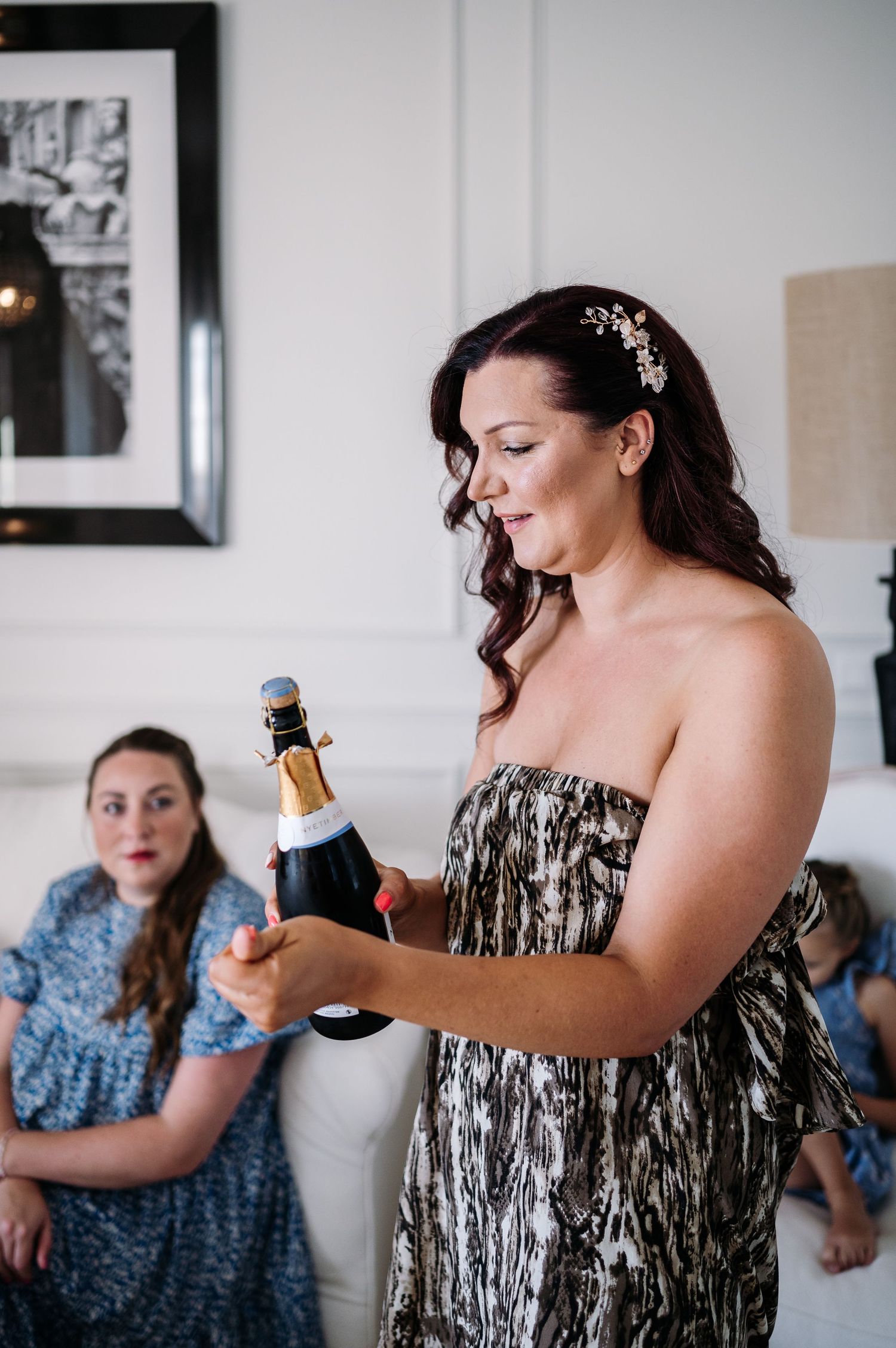 Person in a black and silver dress opening champagne bottles during celebration.