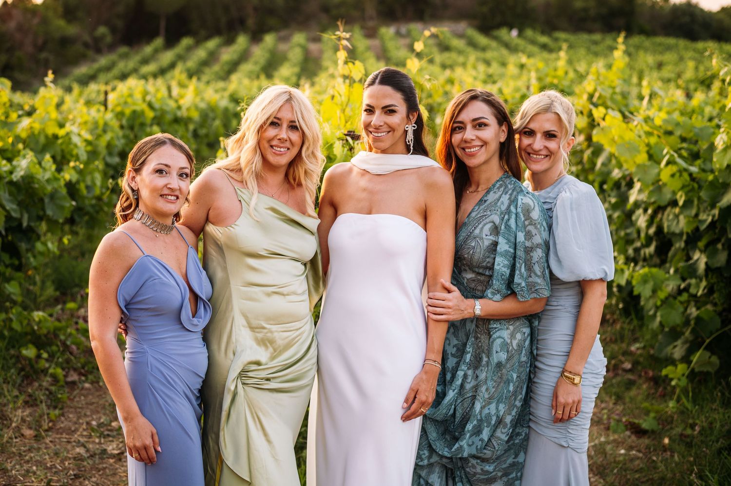 Group of friends posing together in a vineyard during sunset.