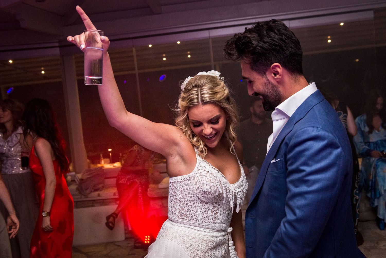 Guests in formal attire dancing and celebrating at a dimly lit wedding reception.