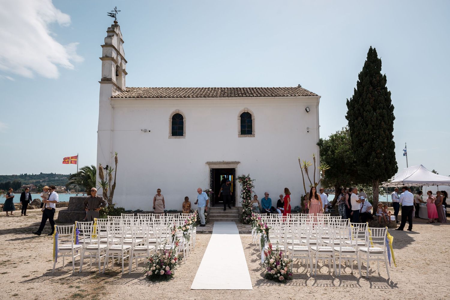 A white Mediterranean church with outdoor seating arranged for a wedding ceremony.