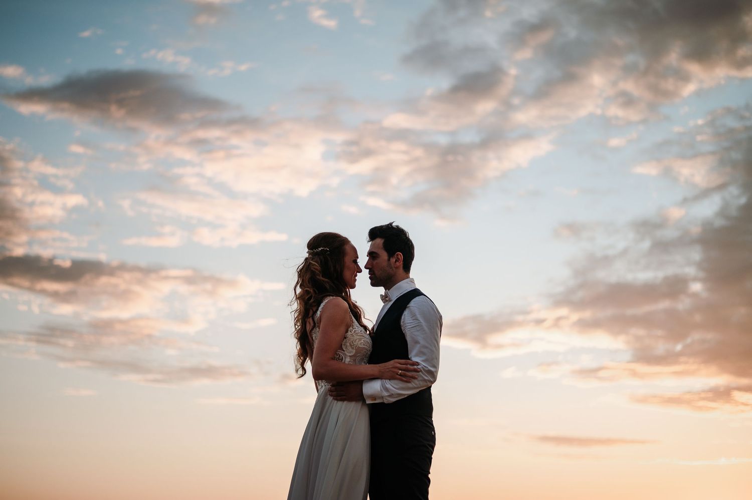 Romantic couple embraces on the beach during a golden sunset wedding photoshoot.