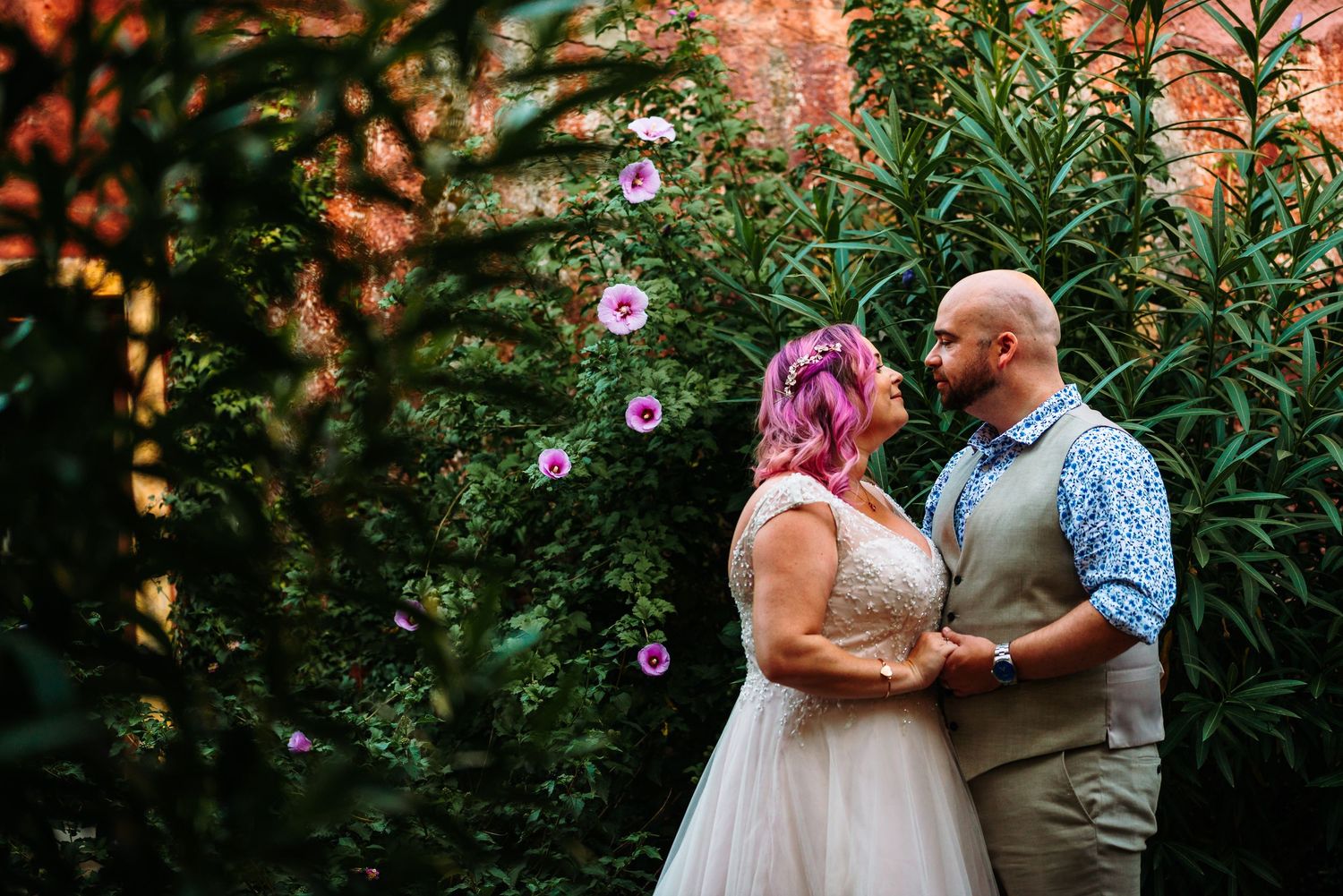 Couple shares romantic moment in a blooming garden with pink flowers.