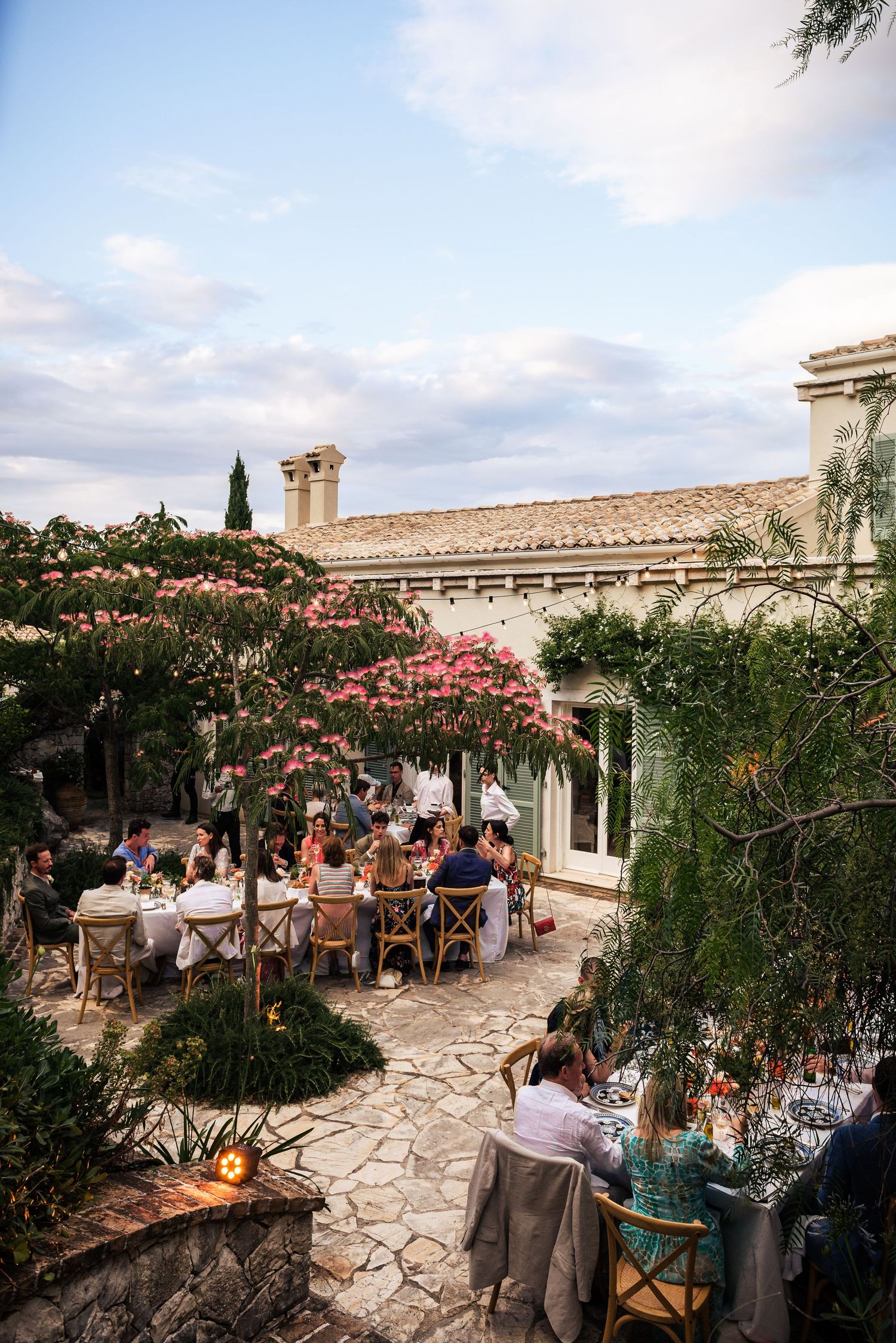 Mediterranean-style stone patio with climbing vines hosts wedding guests during reception.