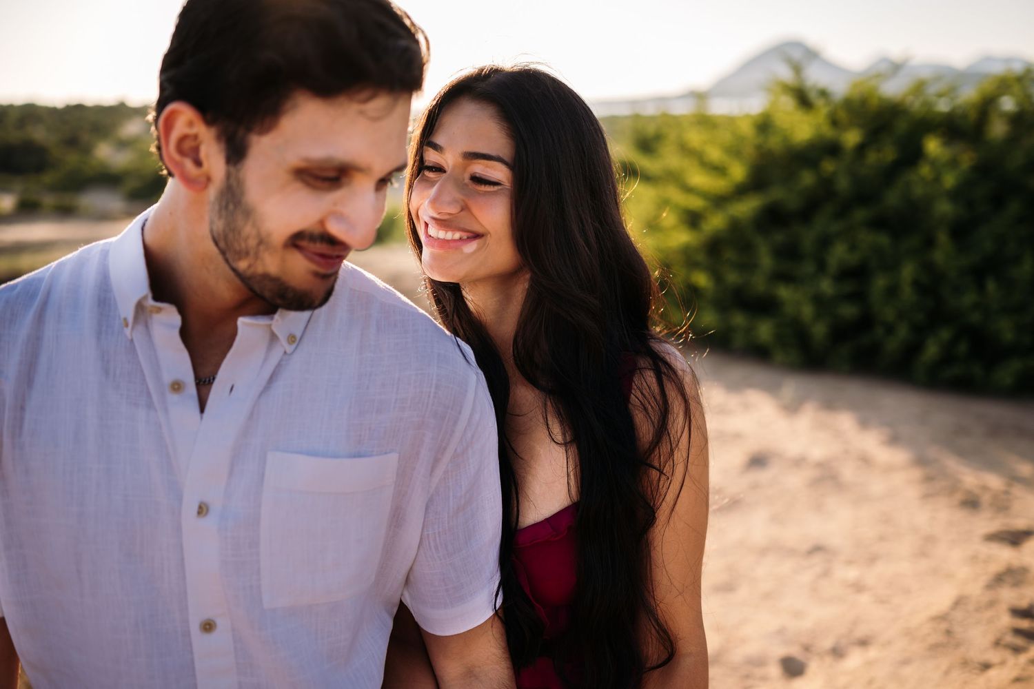 A couple sharing intimate moments during a sunset beach photoshoot.