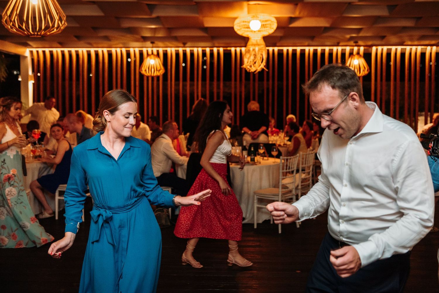 Wedding reception dance floor filled with guests enjoying the celebration under warm lighting.