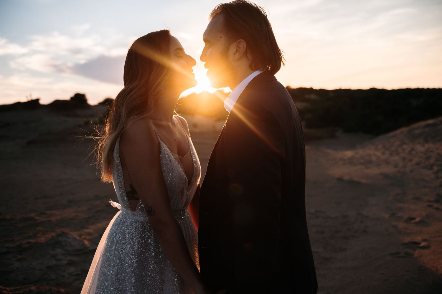 Intimate wedding couple moment captured in golden sunlight on beach.