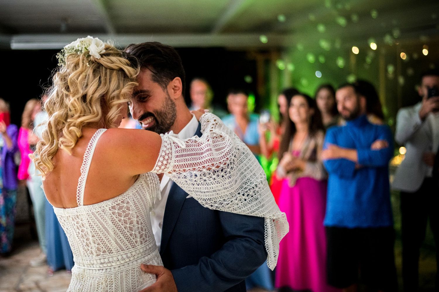 Couple shares first dance under string lights at outdoor wedding reception.