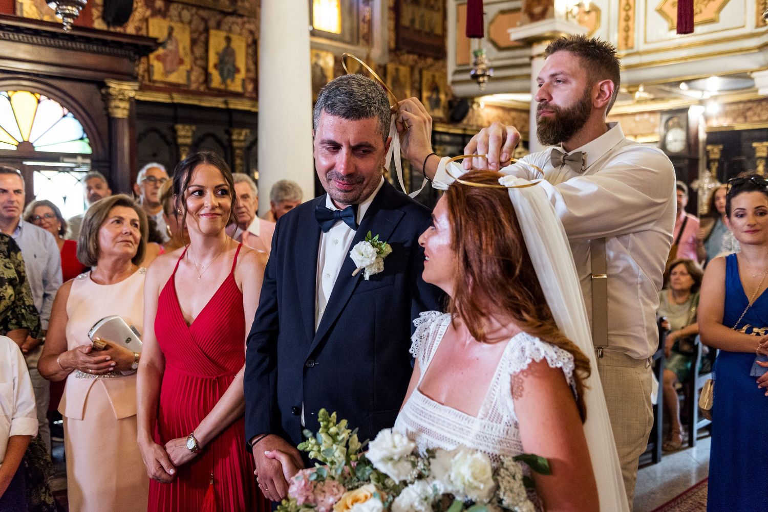 Wedding ceremony in a grand church with ornate gold decorations and white floral arrangements.