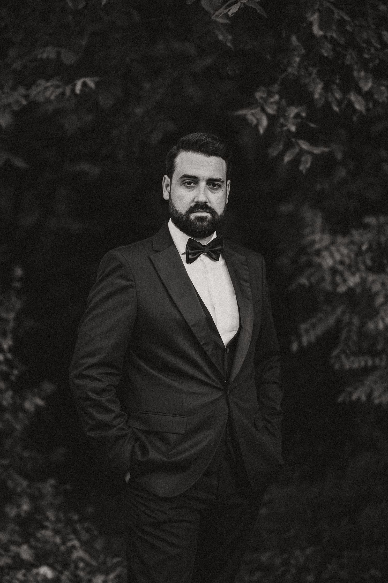 Dramatic black and white portraits of a groom in a tuxedo against a dark background.