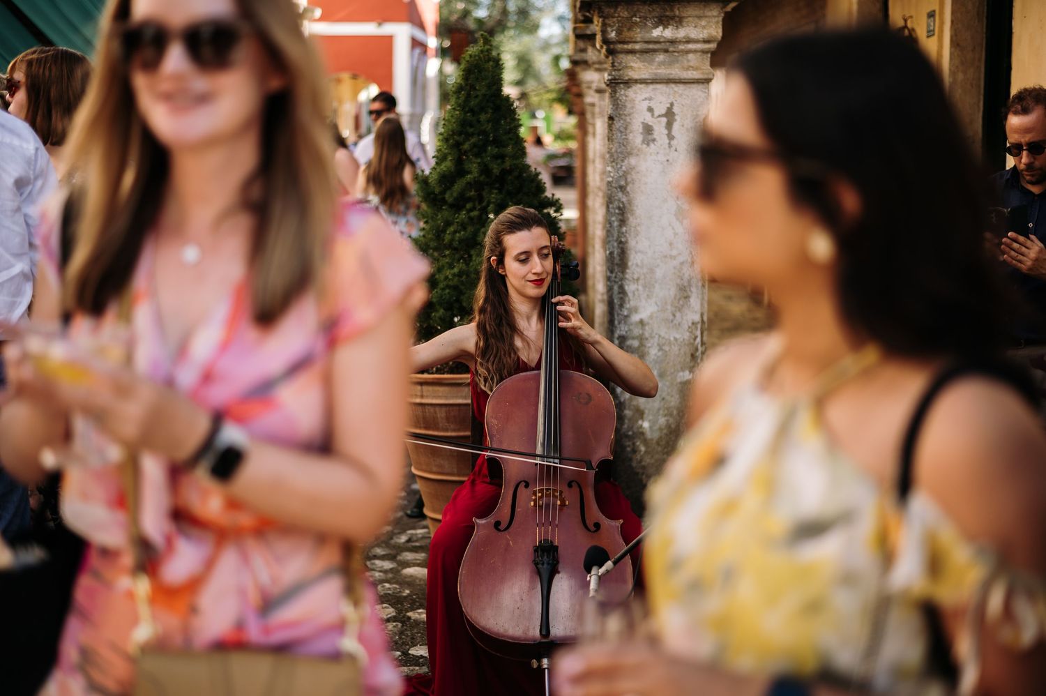 Cellist performs among guests at an outdoor garden party.