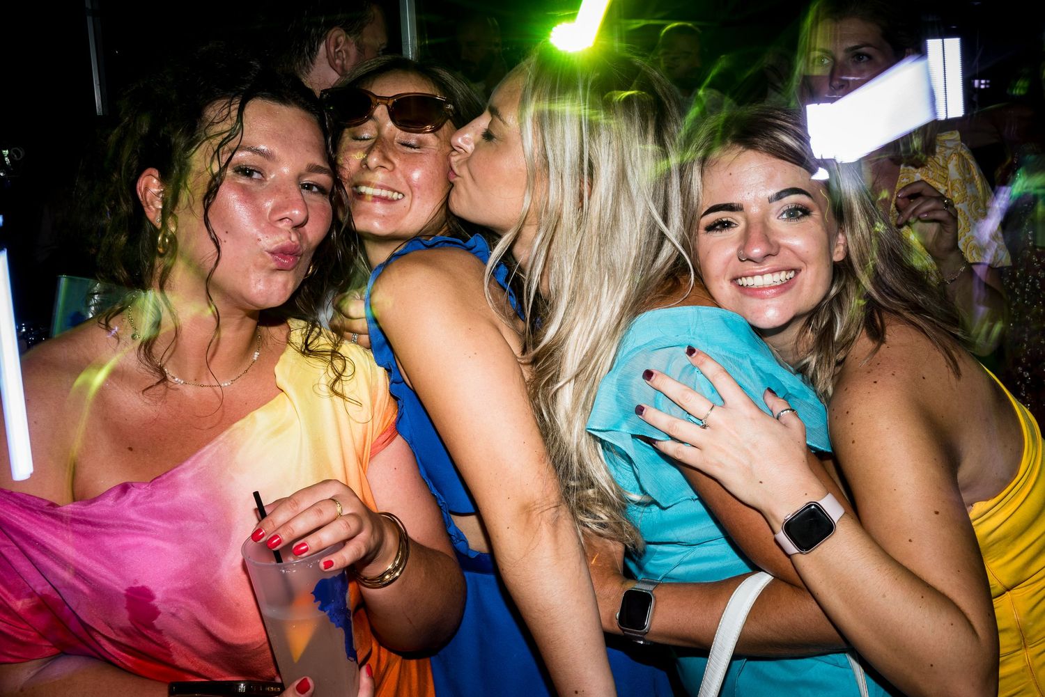 People dancing and having fun at a party with bright neon lights and vibrant atmosphere.