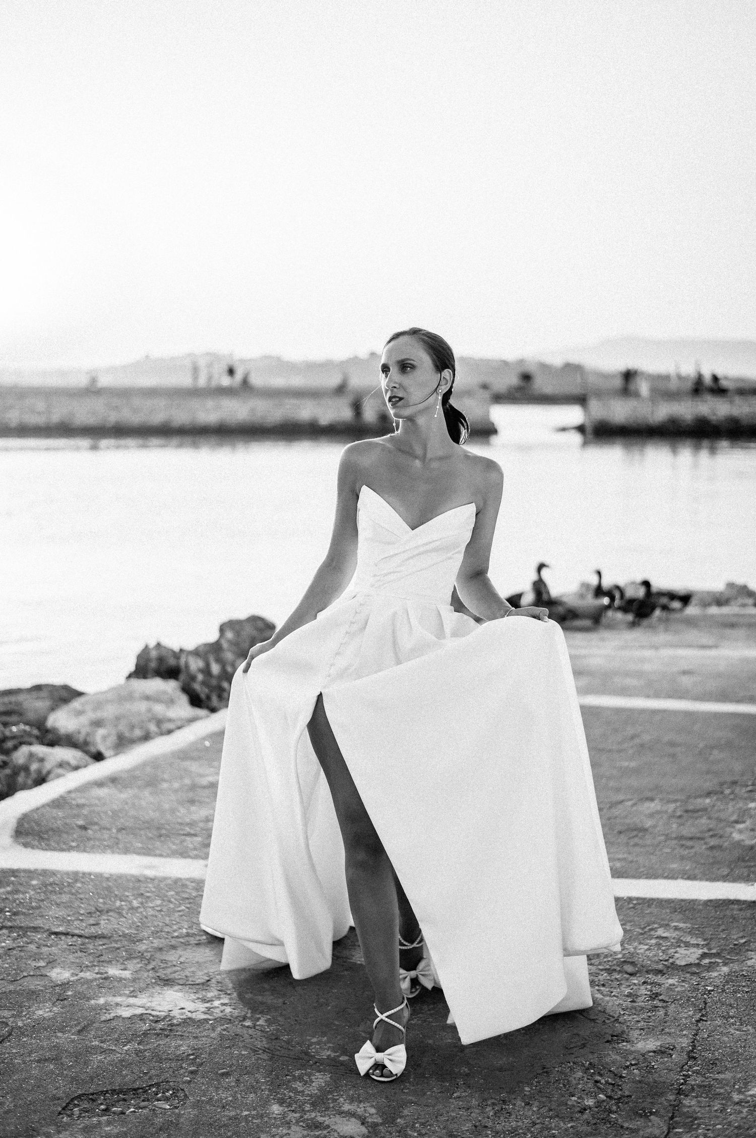 Artistic black and white photos of bride in flowing dress by the seaside.