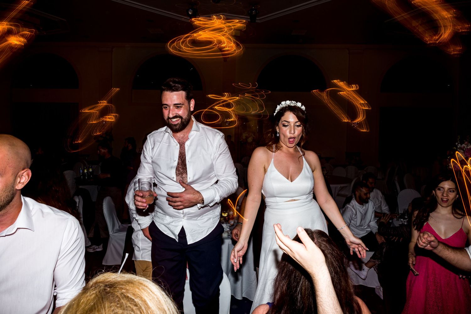 Wedding reception dance floor filled with guests celebrating in a dark venue with ambient lighting.