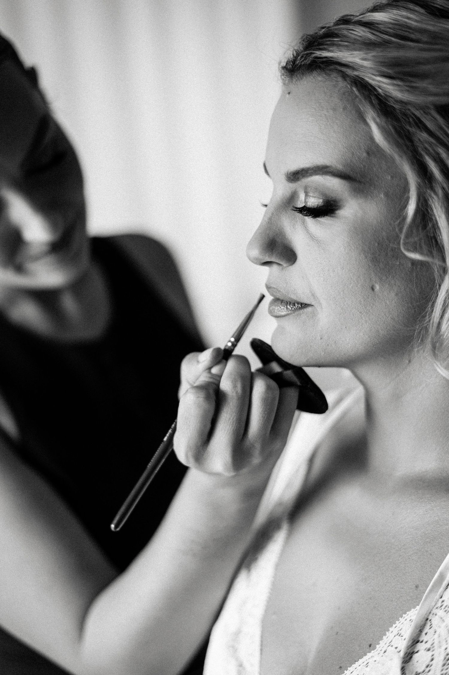 Close-up shots of makeup application in dramatic black and white.