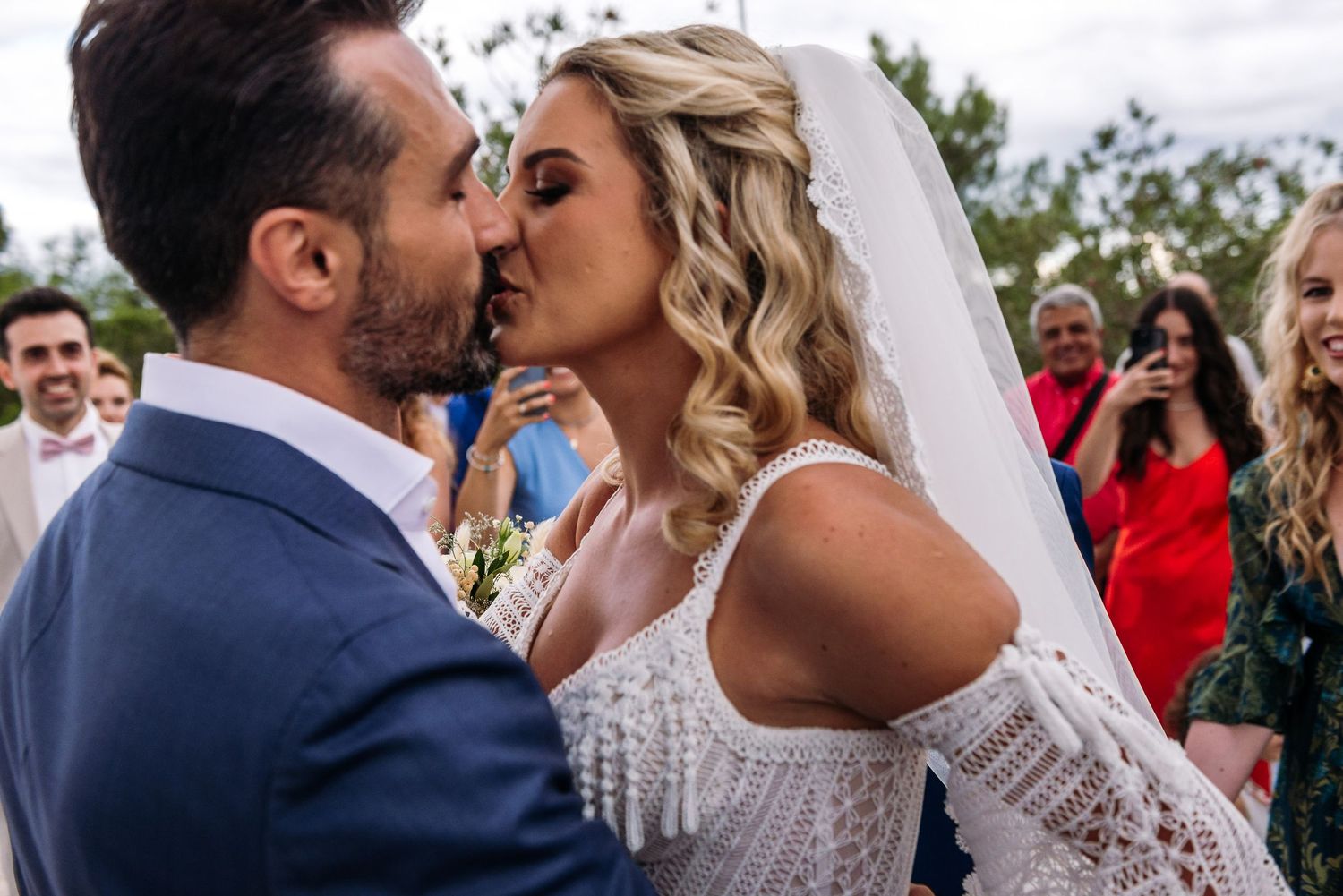 Romantic wedding ceremony moment at a Mediterranean white chapel with guests watching.
