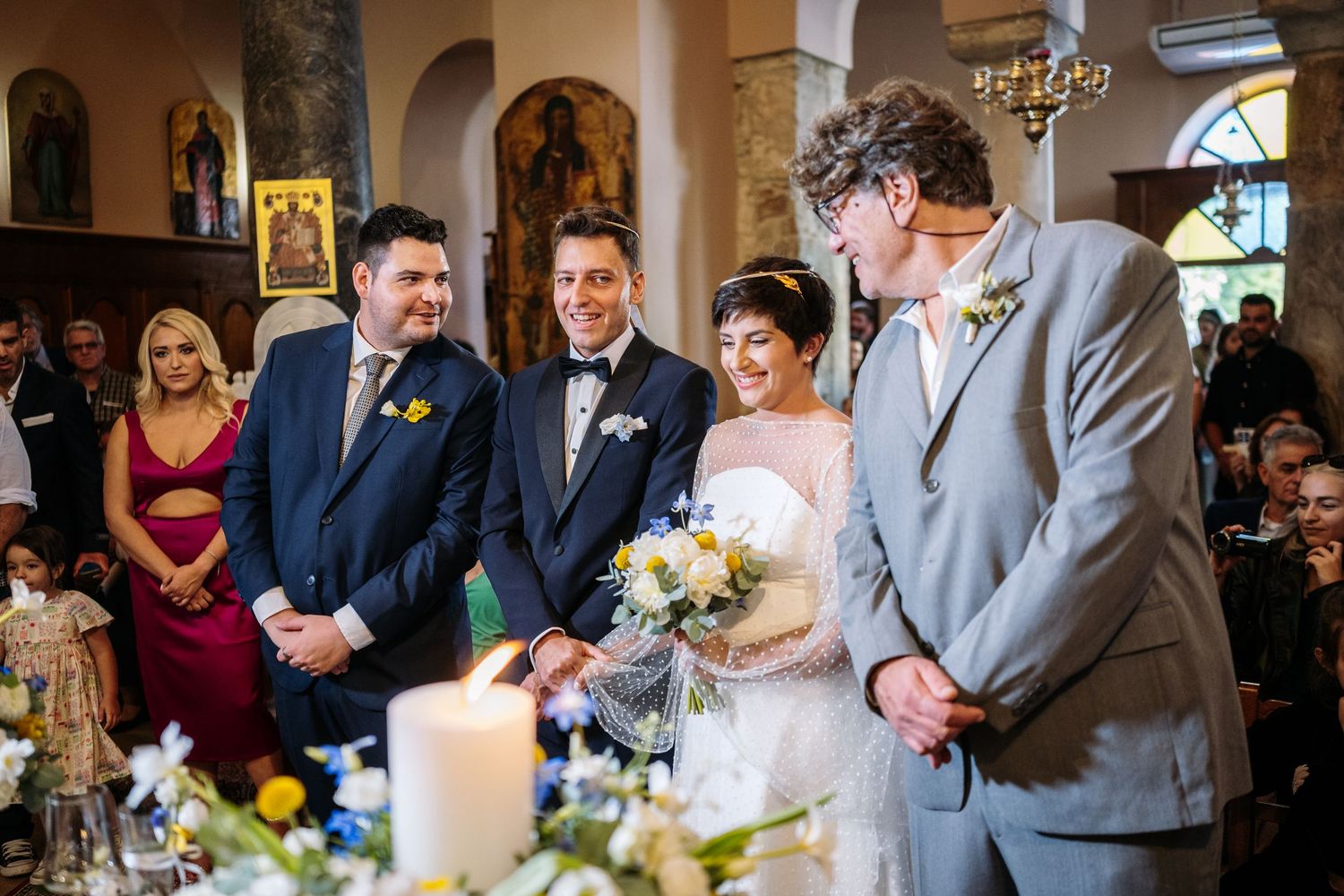 Wedding party gathered in historic church with arched columns and warm lighting.