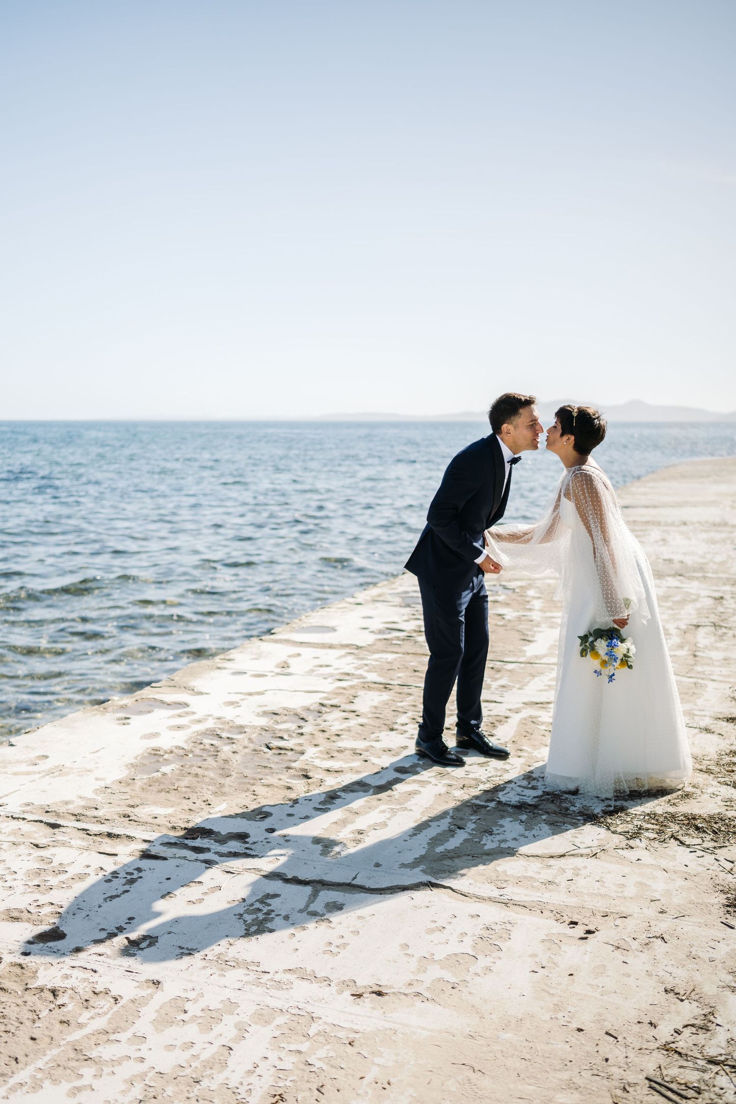 Wedding couple creates shadow silhouettes during their beach photoshoot.