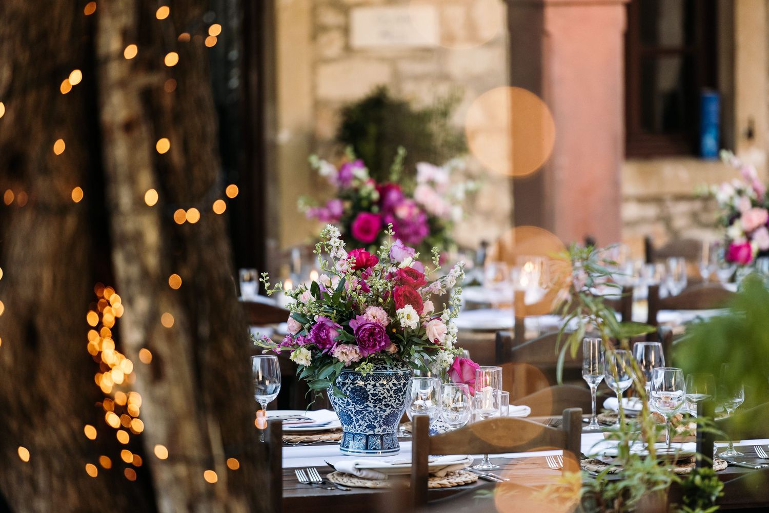 Romantic evening reception table setting with twinkling lights and floral centerpieces.