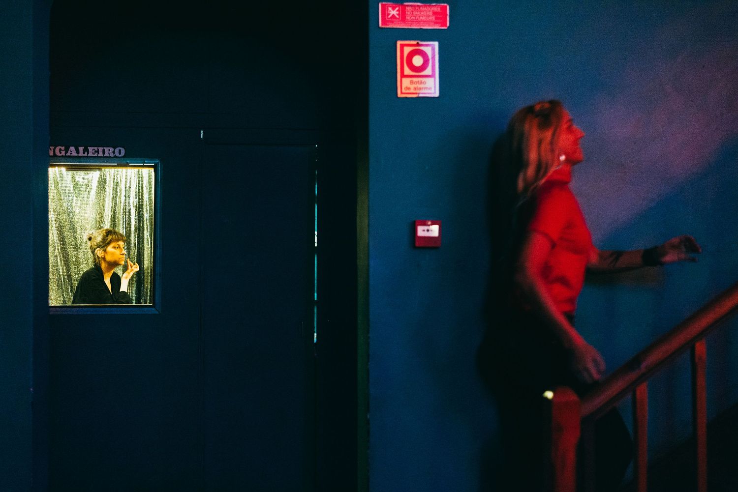 Dark corridor with red emergency lighting and exit signs creating an eerie atmosphere.