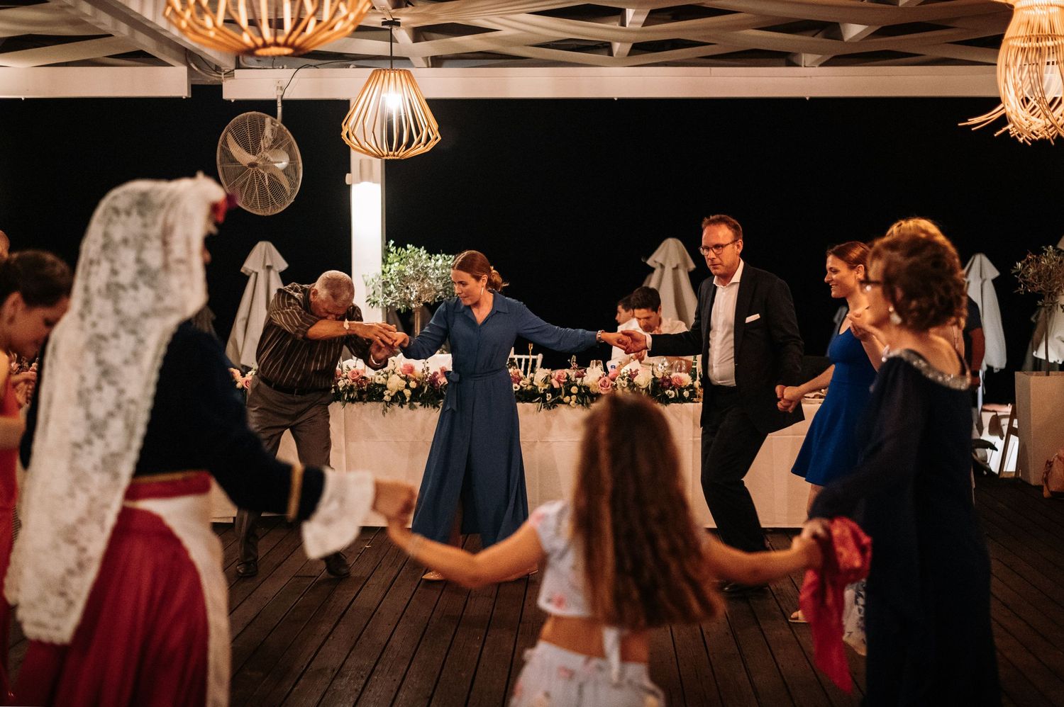 Wedding reception dance party with guests celebrating under warm lighting.