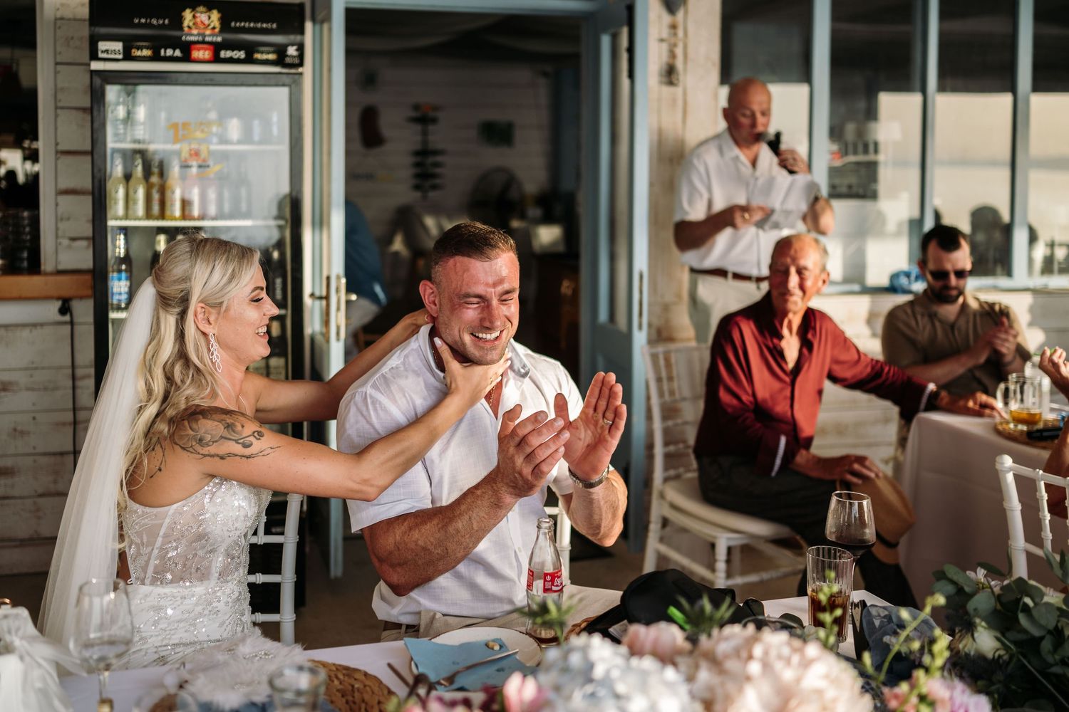 Wedding guests share joyful laughter and emotional moments during a reception celebration.